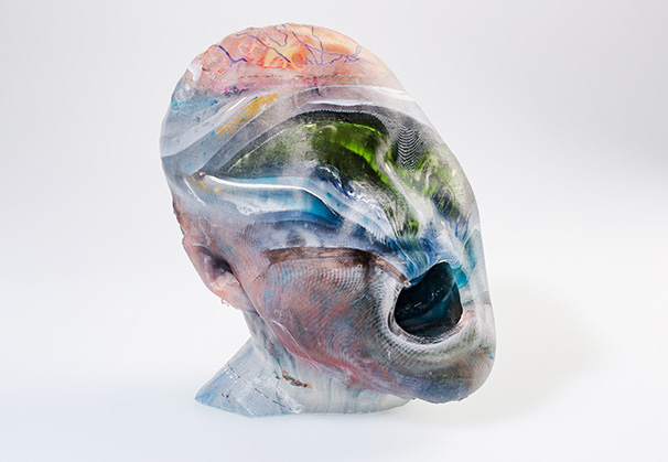 <i>Encyclopaedia Form 1</i>, 2019; 35 x 20 x 20 cm; screenprinted and cast glass; based on a 3D scan of the artist’s head, screenprinted images are layered and fused into a mould in which imagery shifts and warps in the melting process
